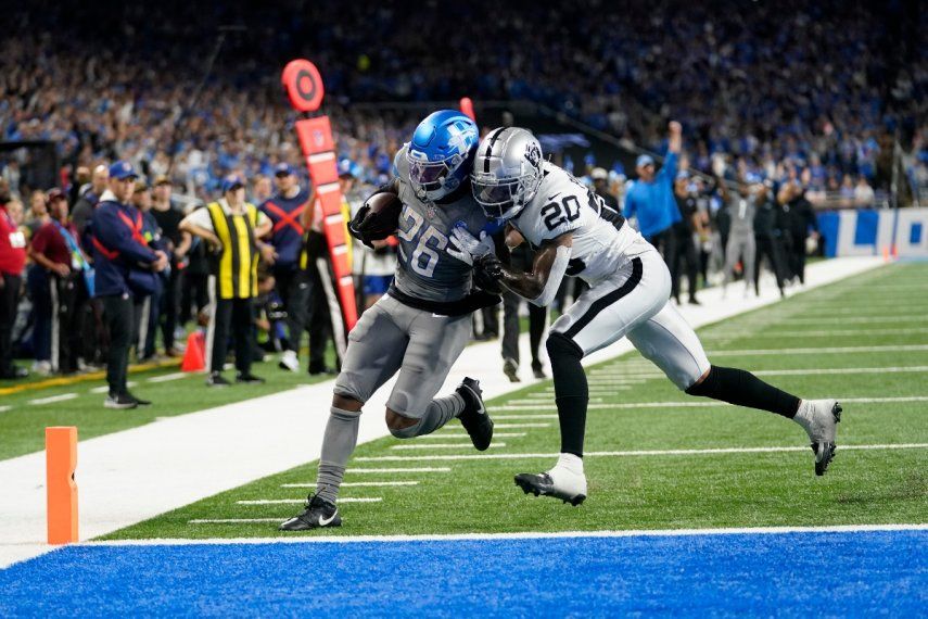 Jahmyr Gibbs (26), corredor de los Lions de Detroit, se enfila a la zona de anotación ante el intento de contenerlo del safety Isaiah Pola-Mao (20), de los Raiders de Las Vegas, después de un acarreo de 27 yardas durante la segunda mitad del juego de la NFL, el lunes 30 de octubre de 2023, en Detroit.&nbsp;