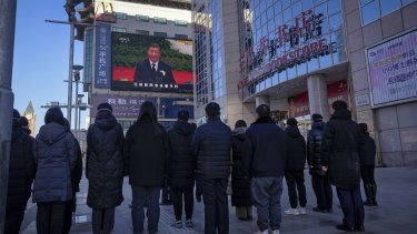 Gente mirando una emisión en vivo del funeral del expresidente de China Jiang Zemin, en la que el actual presidente de China, Xi Jinping, ofrece un discurso, en una pantalla en la calle comercial de Wangfujing en Beijing, el martes 6 de diciembre de 2022.