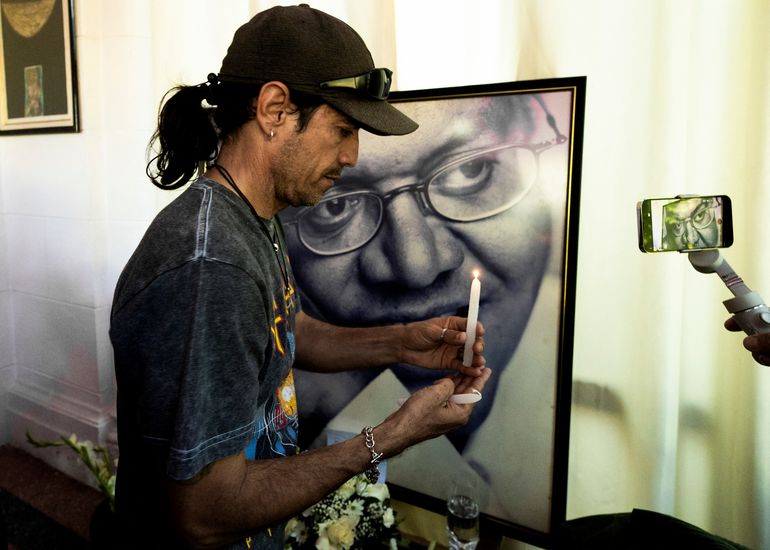 Un hombre enciende una vela frente a una fotografía del fallecido cantautor cubano Pablo Milanes, durante un evento de homenaje en el estudio de grabación de PM Records en La Habana, el 22 de noviembre de 2022.