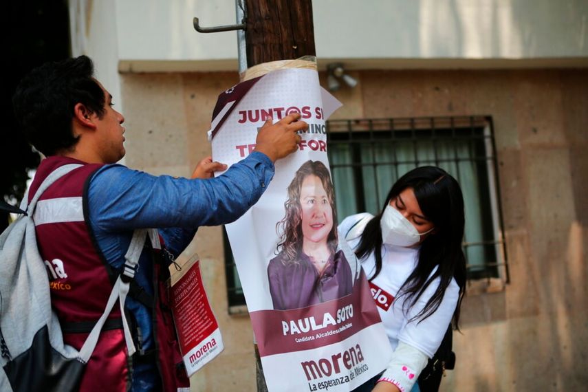 Simpatizantes de la candidata a la alcaldía del partido gobernante Morena, Paula Soto, colocan un cartel en un poste eléctrico en el último día de campaña previo a las elecciones intermedias del 6 de junio, en la Ciudad de México, el sábado 29 de mayo de 2021.