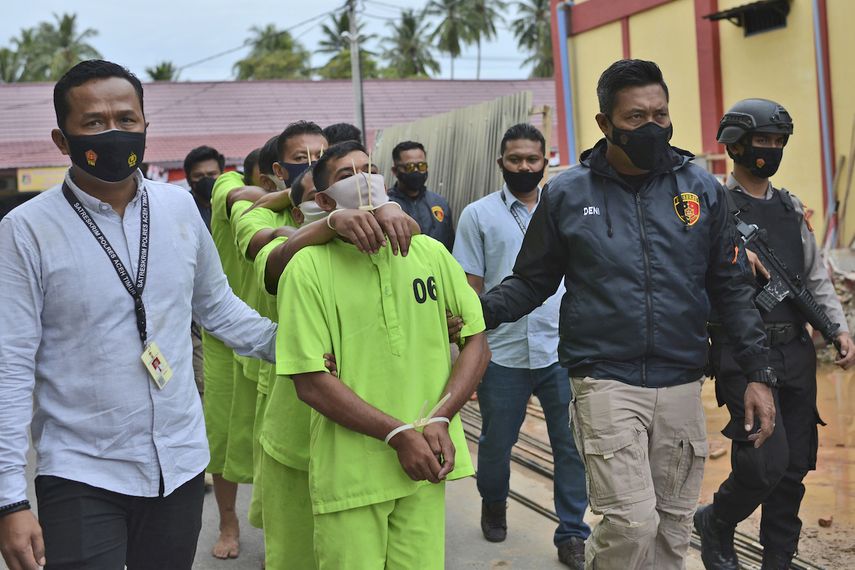 Policías escoltan a un presunto cazador de elefantes y los compradores del marfil para su presentación en una conferencia de prensa en el cuartel general policial en Aceh Oriental, Indonesia, el jueves, 19 de agosto del 2021.&nbsp;