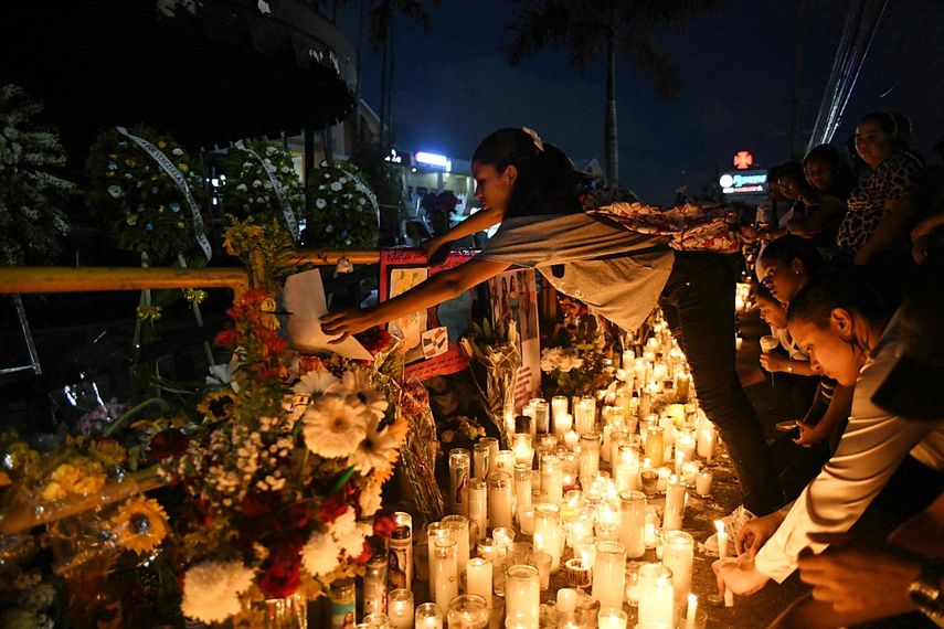Una mujer enciende una vela mientras amigos y familiares rinden homenaje a las víctimas frente a la discoteca Jet Set en Santo Domingo el 12 de abril de 2025.