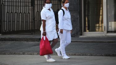 Dos enfermeras usas mascarillas faciales mientras caminan por una calle en La Habana, Cuba.