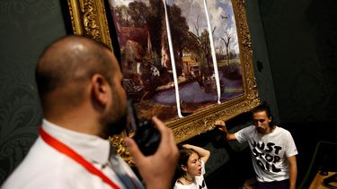 Activistas del grupo de campaña Just Stop Oil, con las manos pegadas al marco de la pintura The Hay Wain del artista inglés John Constable, pero cubiertos en una versión simulada sin fecha que incluye carreteras y aviones, protestan contra el uso de combustibles fósiles, en la National Gallery de Londres el 4 de julio de 2022. &nbsp;