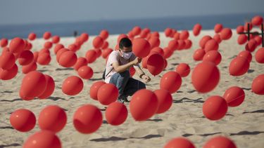 Un hombre ayuda a colocar globos rojos en la arena de la playa Copacabana durante un tributo organizado por R&iacute;o de Paz para las v&iacute;ctimas de COVID-19 cuando el pa&iacute;s se acerca a las 100.000 muertes por el nuevo coronavirus, en R&iacute;o de Janeiro, Brasil, el s&aacute;bado 8 de agosto de 2020.