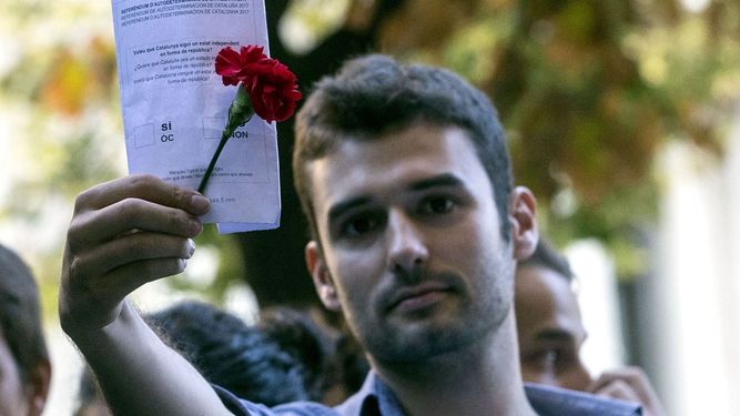 Un joven muestra una papeleta del referéndum durante la concentración ante la consellería de Economía, en la que se protesta por los registros que la Guardia Civil está realizando para recabar indicios relacionados con el referéndum del 1-O, suspendido por el Tribunal Constitucional.&nbsp;
