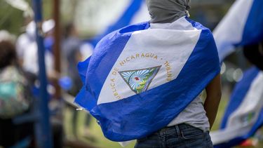 Una joven con la cara tapada y la bandera de Nicaragua participa en una de las protestas en el país centroamericano.&nbsp;
