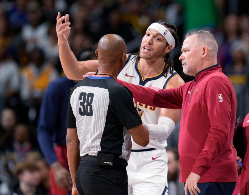 El alero Aaron Gordon, centro, de los Nuggets de Denver, discute con el árbitro Michael Smith, izquierda, después de que le marcara una falta, mientras el coach Michael Malone observa en la primera mitad del juego de baloncesto de la NBA en contra de los Warriors de Golden State, el lunes 25 de diciembre de 2023, en Denver.