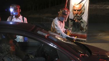 Trabajadores con trajes protectores desinfectan autos que entran a un autocine en un estacionamiento junto a la torre Milad, en Teherán.&nbsp;