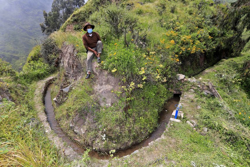Foto de la hoja publicada por la organización Aquafondo de un campesino sentado junto a parte de una red prehispánica de canales de piedra que surca las laderas de los cerros que transportan agua para la agricultura, en San Pedro de Casta, provincia de Lima, Perú, el 18 de abril. 2021. &nbsp;