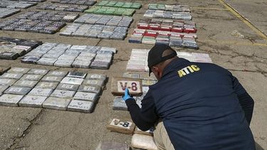 Esta fotografía de la ATIC divulgada por la ATIC muestra a un integrante de la Agencia Técnica de Investigación Criminal (ATIC) mientras contabiliza al menos 911 kilos de cocaína incautados en Ironia, Honduras, el 6 de abril de 2021. La droga fue trasladada en dos aviones del Honduras. Fuerza Aérea a la Base Militar Hernán Acosta Mejía en Tegucigalpa.
