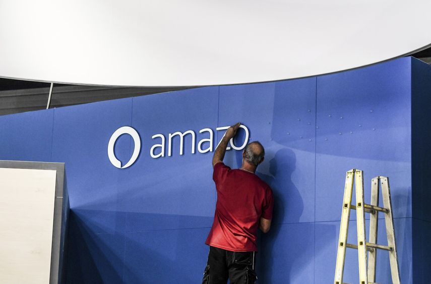 Un trabajador ajusta un letrero de Amazon.&nbsp;