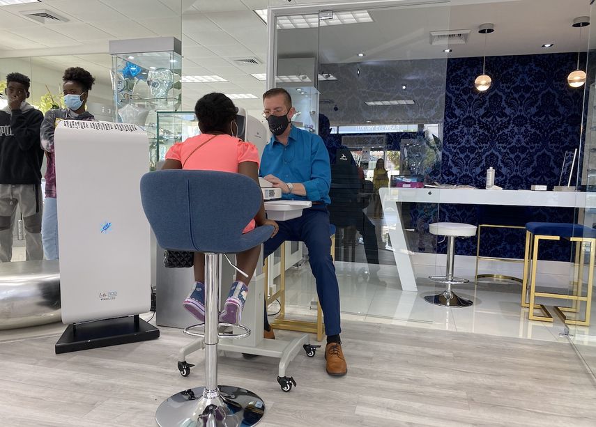 El optometrista Brian Koropatnick hace un chequeo de la vista a un niño durante un evento de ayuda para pequeños de Miami, en la óptica Oberti Luxury Eyewear.