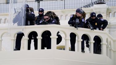 Agentes de la policía observan a unos manifestantes que tratan de pasar a través de una barrera de la policía, el miércoles 6 de enero de 2021, en el Capitolio, en Washington.