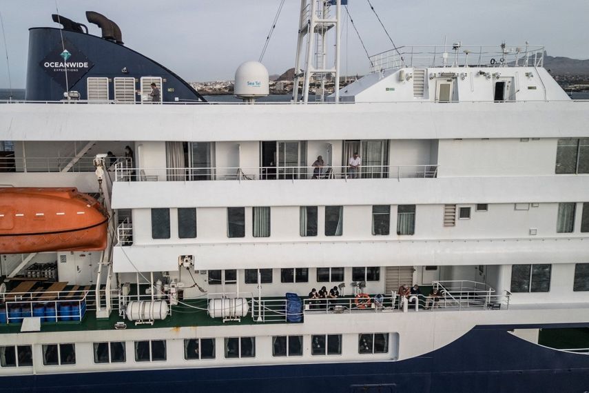 Esta vista aérea muestra a los pasajeros observando cómo personal sanitario, invisible para el público, ayuda a los pacientes a subir a un bote desde el crucero MV Hondius, mientras este se encontraba anclado frente al puerto de Praia, la capital de Cabo Verde, el 6 de mayo de 2026. &nbsp;