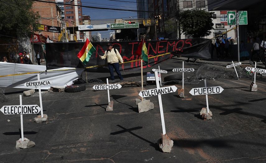 Una mujer sostiene una bandera nacional&nbsp;frente a&nbsp;una barricada durante una protesta contra la reelecci&oacute;n del presidente Evo Morales en La Paz, Bolivia, el lunes 28 de octubre de 2019.&nbsp;