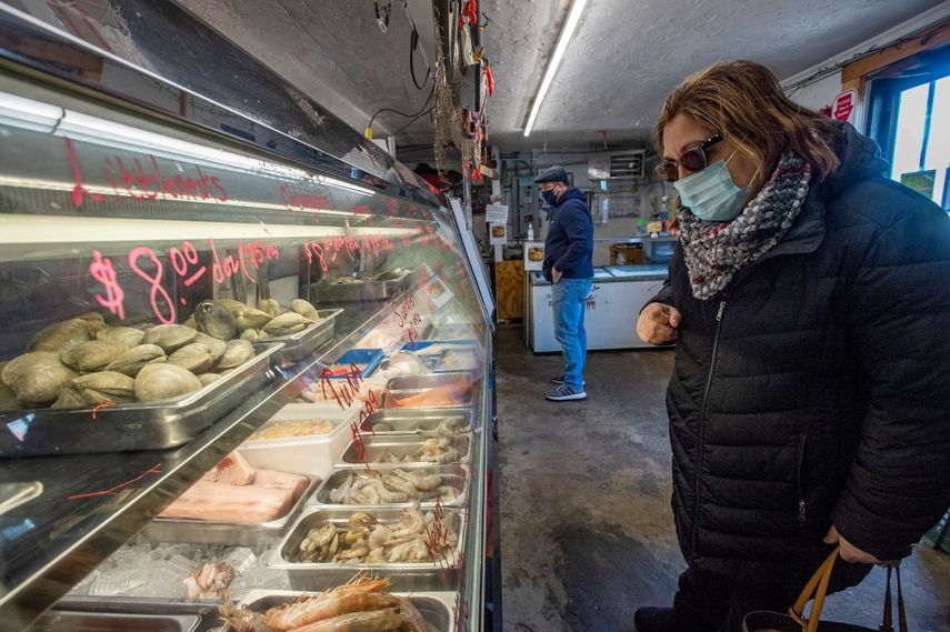 Una clienta observa los precios y productos del mar en un pequeño mercado.