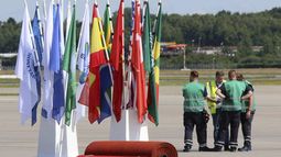 Operarios esperan junto a banderas y alfombras rojas preparadas en el aeropuerto para la llegada de los líderes de los estados que acudirán a la cumbre del G20, en&nbsp;Hamburgo.
