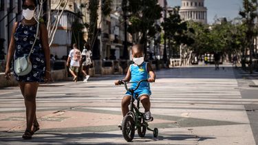 Una mujer acompaña a un niño en bicicleta, ambos con mascarillas protectoras como medida de precaución en medio de la propagación del nuevo coronavirus, en La Habana, Cuba, el viernes 3 de julio de 2020. 