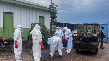 Personal médico con equipo de protección personal (EPP) se encuentra junto al ataúd de un paciente fallecido por ébola, sobre un remolque en un hospital de Rwampara el 21 de mayo de 2026.