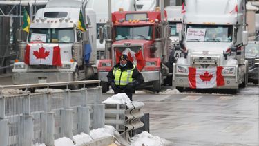 Un policía de pie frente a camiones que bloquean el paso hacia las calles del centro como parte de una protesta contra las medidas impuestas por el COVID-19, el miércoles 9 de febrero de 2022, en Ottawa.&nbsp;