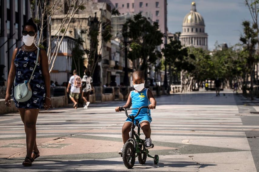 Una mujer acompaña a un niño en bicicleta, ambos con mascarillas protectoras como medida de precaución en medio de la propagación del nuevo coronavirus, en La Habana, Cuba, el viernes 3 de julio de 2020. 