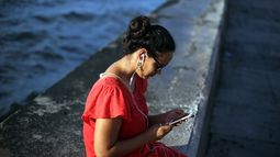 Una mujer accede a internet a través de su teléfono móvil en el malecón habanero.&nbsp;