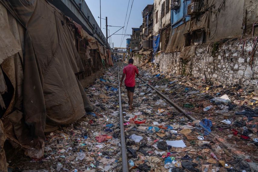 Un hombre camina en una vía ferroviaria repleta de plásticos y otros desechos en el Día de la Tierra, en Mumbai, India, el 22 de abril de 2024.