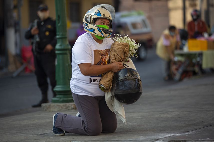 En esta fotografía de archivo del 9 de abril de 2020, una motociclista reza de rodillas frente a la iglesia cerrada de la Candelaria durante la Semana Santa en la Ciudad de Guatemala, donde por primera vez en cientos de años la procesión católica de una imagen de Jesucristo, conocida como Cristo Rey, fue cancelada debido a la pandemia de COVID-19.