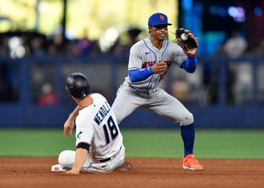 El campocorto de los Mets de Nueva York, Francisco Lindor, atrapa la pelota mientras Joey Wendle (18) de los Marlins de Miami es expulsado durante la octava entrada de un juego de béisbol, el domingo 2 de abril de 2023, en Miami. 