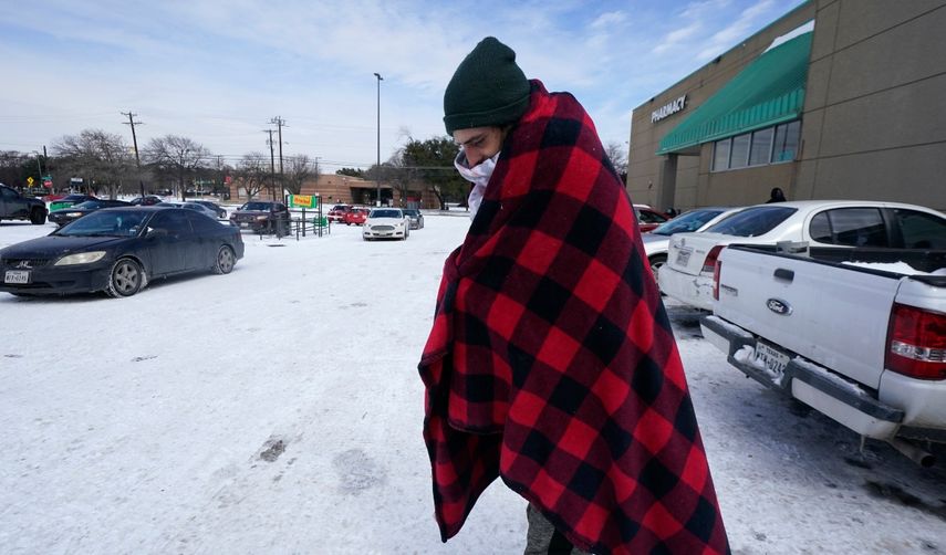 Cody Jennings utiliza un cobertor para mantenerse caliente afuera de una tienda en Dallas, el martes 16 de febrero de 2021.