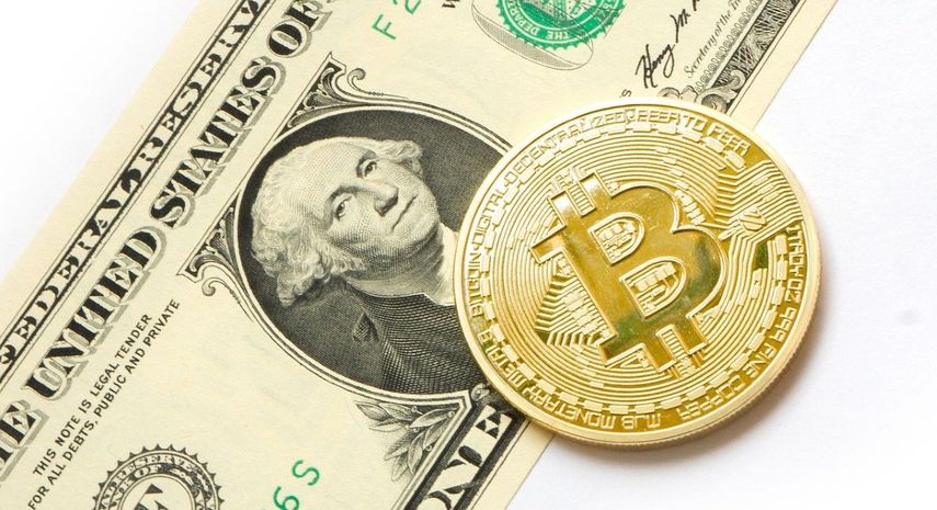 El simbolismo de una moneda de bitcoin sobre un billete de dólar.