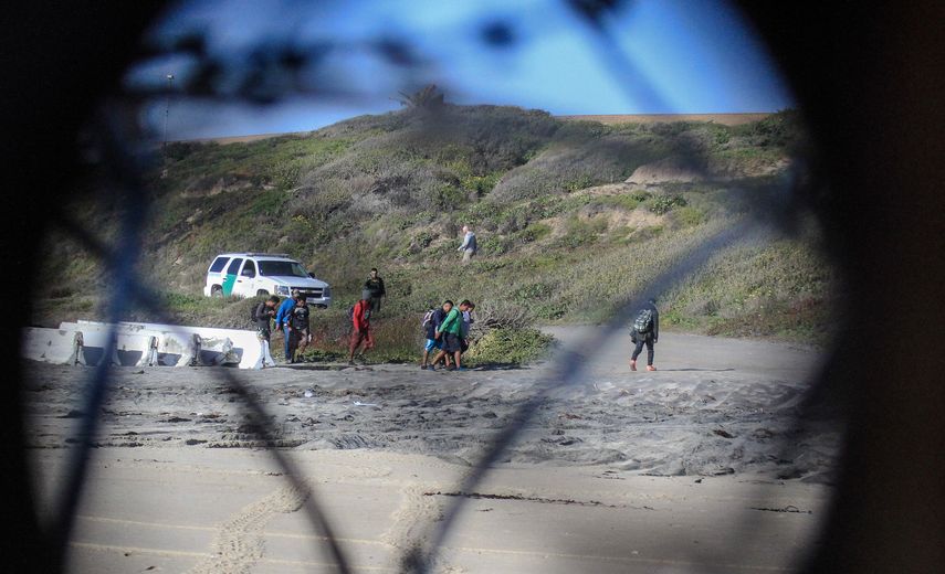 Decenas de migrantes caminan por territorio estadounidense tras saltar la valla metálica ubicada en zona de Playas Tijuana, en el estado mexicano de Baja California (México).&nbsp;
