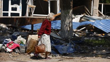 Una civil camina entre un inmueble destruido en Mariúpol, territorio bajo control del gobierno de la República Popular de Donetsk, en el este de Ucrania, el viernes 27 de mayo de 2022. 