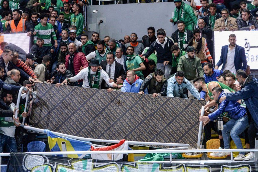 Varios fanáticos intentan despejar el área luego de un derrumbe de gradas durante un partido de baloncesto en El Cairo.
