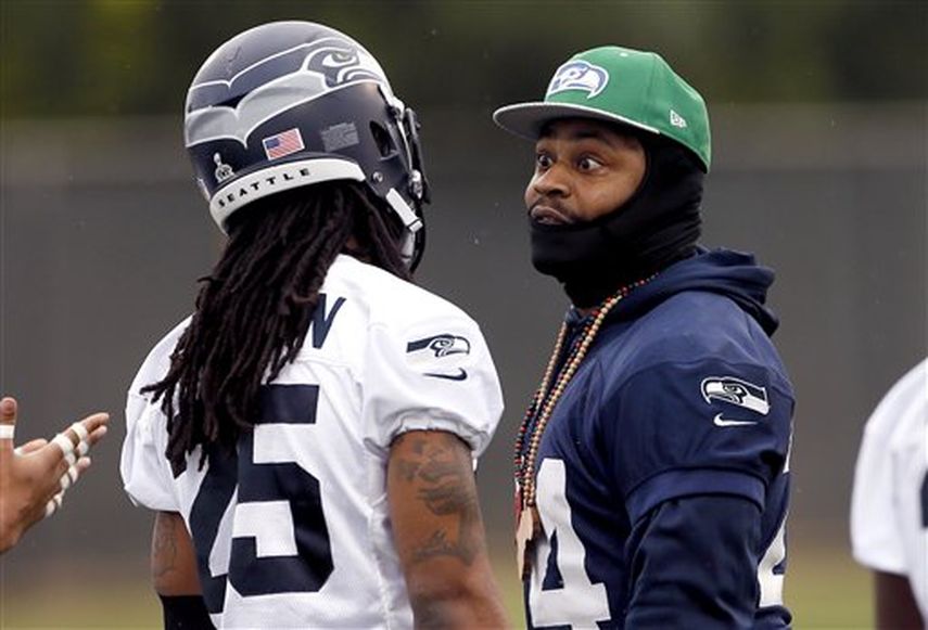 Marshawn Lynch de los Seahawks de Seatte, derecha, conversa con Richard Sherman durante un entrenamiento previo al Súper Bowl. (AP)