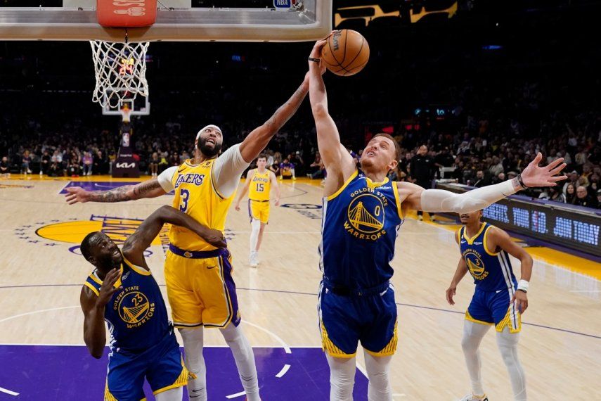 El alero de los Lakers de Los Ángeles, Anthony Davis, va por el rebote frente a Donte DiVincenzo y Draymond Green de los Warriors de Golden State en el juego 6 de la serie de semifinales de la Conferencia Oeste, el viernes 12 de mayo del 2023.