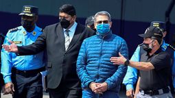 El expresidente de Honduras, Juan Orlando Hernández, es escoltado por el ministro de Seguridad, Ramón Sabillon, hacia un avión de la Agencia Antidrogas de los Estados Unidos (DEA), durante su extradición a Estados Unidos en la Base de la Fuerza Aérea, en Tegucigalpa, el 21 de abril de 2022.