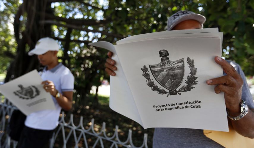 Dos personas leen en La Habana&nbsp;el tabloide con el texto del Proyecto de Constitución de la República de Cuba.