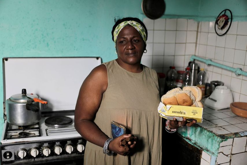 María de los Ángeles Pozo, trabajadora retirada de una escuela, posa para una foto en su cocina con algunos de los alimentos subvencionados que recibió por con la libreta de abastecimiento estatal en La Habana, Cuba, el miércoles 6 de marzo de 2024. 
