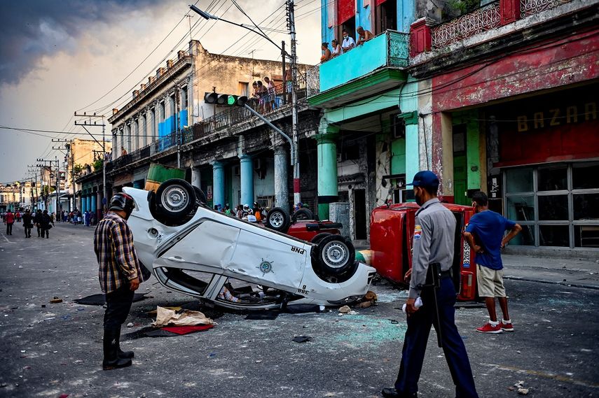 Los coches de la policía se ven volcados en la calle en el marco de una manifestación contra Miguel Díaz-Canel en La Habana, el 11 de julio de 2021.&nbsp;&nbsp;