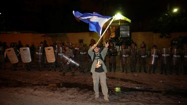Un simpatizante del candidato opositor Salvador Nasralla, iza una bandera hondureña frente al cordón policial durante los enfrentamientos que se produjeron entre grupos de seguidores del candidato opositor Salvador Nasralla y las fuerzas de seguridad.&nbsp;