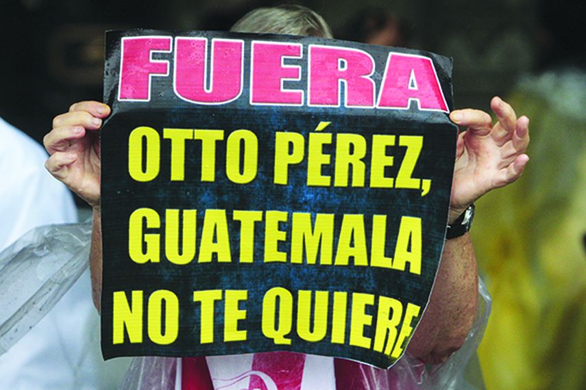 Una mujer sostiene un cartel durante manifestaciones multitudinarias en Guatemala. (CORTESÍA)