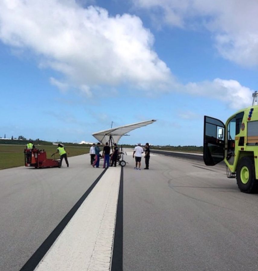 Fotografía proporcionada por la Oficina del Sheriff del condado de Monroe a través de la Florida Keys News Bureau, en la que aparecen empleados del aeropuerto internacional de Key West junto a un ala delta motorizada que aterrizó ilegalmente en el aeropuerto con dos hombres cubanos el sábado 25 de marzo de 2023 en Key West, Florida.