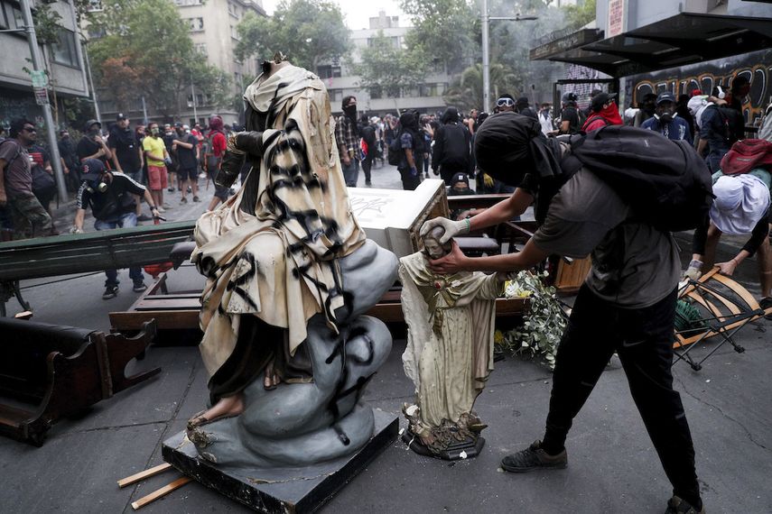 Un manifestante contra el gobierno remueve la cabeza a una estatua de Jesucristo que tom&oacute; de una iglesia para agregarla a una barricada en Santiago de Chile el viernes 8 de noviembre de 2019.