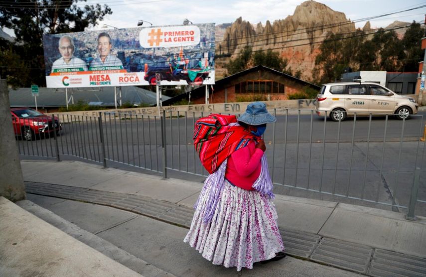 Una mujer camina cerca de un cartel del candidato presidencial Carlos Mesa, del partido Comunidad Ciudadana, en El Alto, Bolivia, un día antes de las elecciones presidenciales.