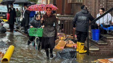 Unos peatones caminan por una acera inundada, el viernes 29 de septiembre de 2023, en el distrito neoyorquino de Brooklyn.