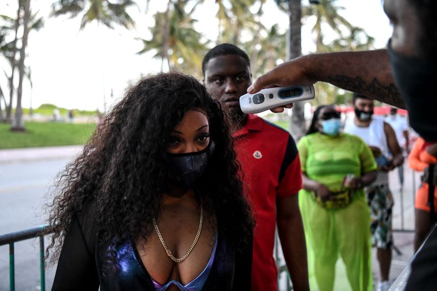 Un guardia de seguridad toma la temperatura a una mujer a la entrada de un restaurante en Ocean Drive en Miami Beach, Florida. Junio 24 de 2020.