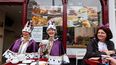 Dos mujeres con coronas toman una taza de té en Windsor High Street antes de un Gran Almuerzo de Coronación organizado en Windsor, el 7 de mayo de 2023. Los británicos planearon miles de fiestas callejeras locales en el segundo día de eventos para conmemorar el coronación del rey Carlos III, que finalizó con un concierto frente a 20.000 personas en el Castillo de Windsor.