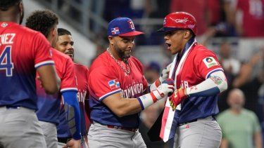 Juan Soto (derecha), de la República Dominicana, recibe una banda presidencial de manos de Nelson Cruz tras disparar un jonrón ante Nicaragua en el Clásico Mundial de Béisbol, el lunes 13 de marzo de 2023, en Miami.